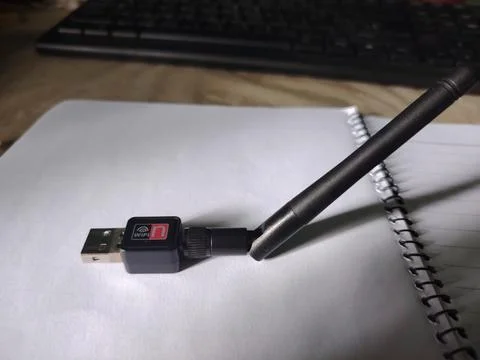 Compact black wireless usb network adapter with an external antenna resting.. Fotos Stock