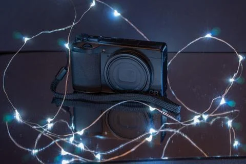 Compact camera stands on a mirror and is illuminated by a LED light chain Stock Photos