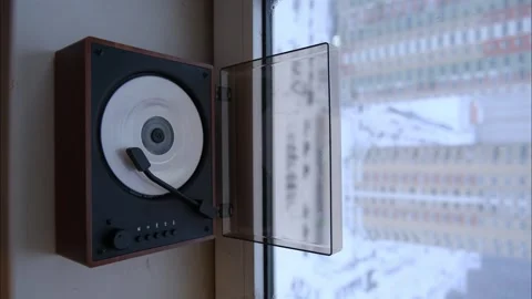 Compact CD player with spinning disc next to a window overlooking apartment Stockbeeldmateriaal 333581280