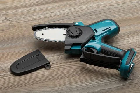 Compact cordless mini chainsaw with sharp metal chain for pruning garden tr.. Stock Photos