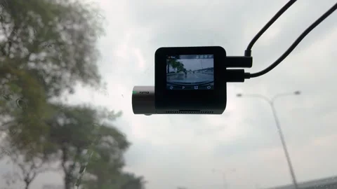 A compact dash cam is mounted to a car windshield 動画素材 317929115