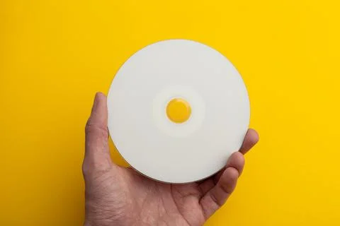 Compact disc with a blank surface in hand on a yellow background Stock Photos