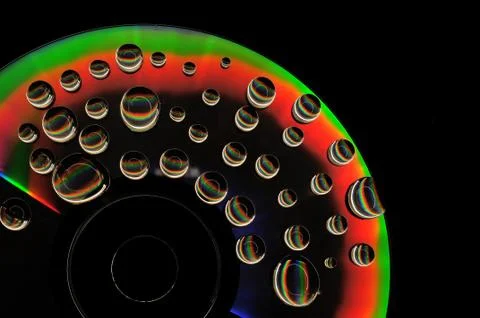 Compact disc cd with water drops on the data surface with a shiny colorful re Stock Photos