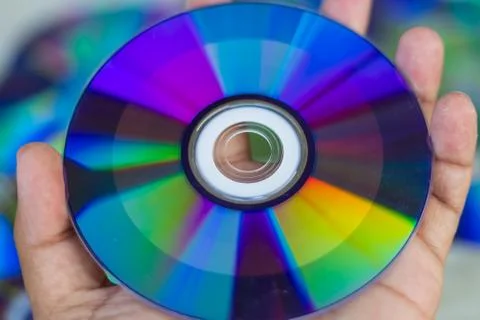 Compact Disc. Holding a CD in hands. The back side of the CD reflects colorfu Stock Photos