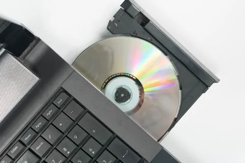 Compact disc inserted in the tray of the SD drive of the laptop on an empty b Stock Photos