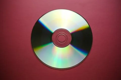 Compact disk close-up on a red burgundy background, outdated data storage Stock Photos