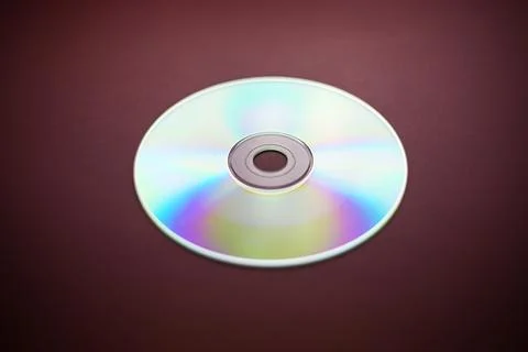Compact disk close-up on a red burgundy background, outdated data storage Stock Photos