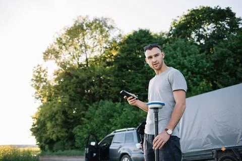 Compact drone hovers in front of farmer with remote controller in his hands. Stock Photos