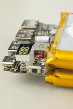 Compact electronics board beside a bright yellow battery Fotos de archivo