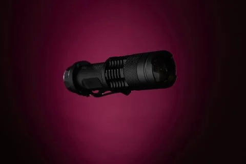 Compact flashlight lying on magenta gradient background minimalist studio sho Stock Photos