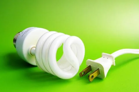Compact fluorescent light bulb and plug, on green Stock Photos