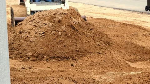 Compact front loader pushes a pile of brown dirt . Stock Footage 154433988