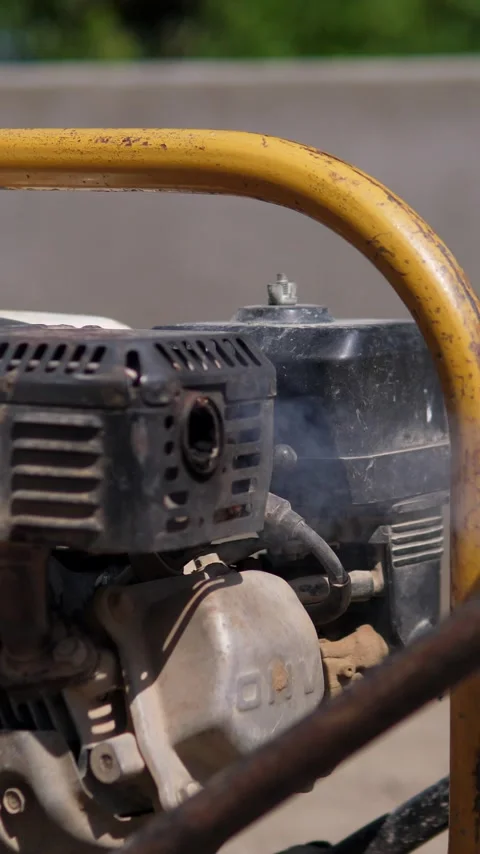 Compact gasoline engine inside yellow metal casing, worn paint, rust, fuel tank 動画素材 347918684