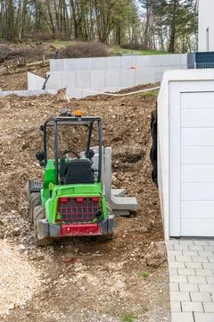 Compact green loader at building foundation excavation Foto stock