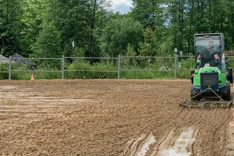 Compact green mini loader tractor levelling sand soil with drag harrow harr.. Photos