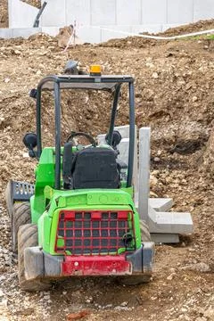 Compact green wheel loader at construction site during earthmoving work. Fotos Stock