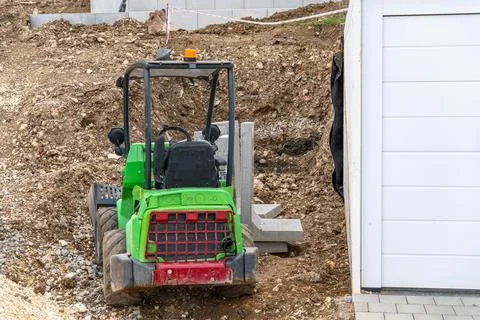 Compact green wheel loader at construction site during earthmoving work. Fotos Stock