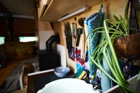 Compact kitchen space in a van with organized utensils, plants, and rustic decor Stock Photos