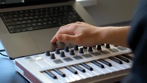 Compact MIDI controller and laptop computer, emphasizing the hands-on creative Stock Footage 321880892