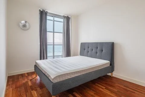 Compact minimalistic cozy double bed in bedroom with wooden laminate flooring Stock Photos