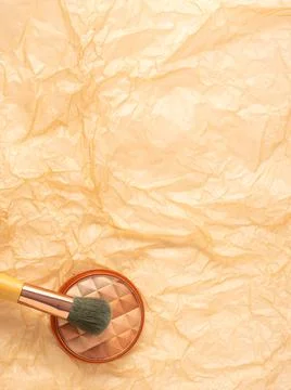Compact multi color face powder on crumpled beige textured background Stock Photos