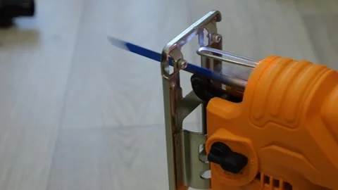 Compact Orange Jigsaw With Blade Oscillating Over Wooden Floor, Focused On Blade Stock Footage 330396398