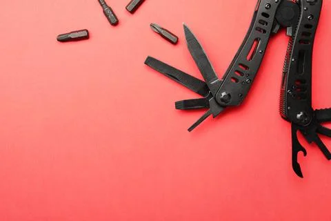 Compact portable black multitool and details on red background, flat lay. Spa Stock Photos