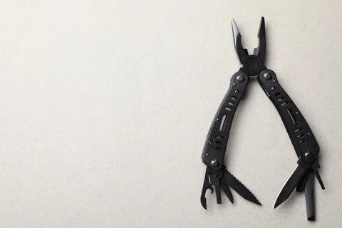 Compact portable black multitool on light grey background, top view. Space fo Stock Photos
