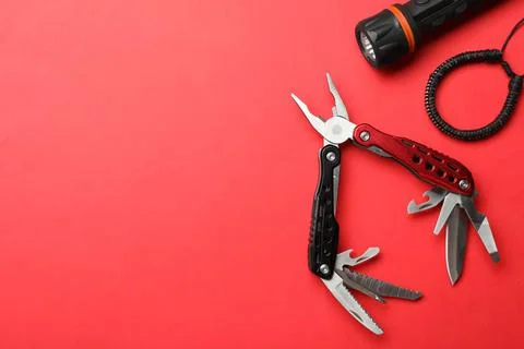 Compact portable multitool, bracelet and flashlight on red background, flat l Stock Photos
