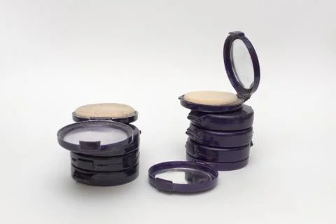 Compact powder boxes in vertical stacks, opened cases contains mirror and spo Stock Photos