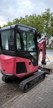Compact red mini excavator at construction site on city street Stock-Fotos