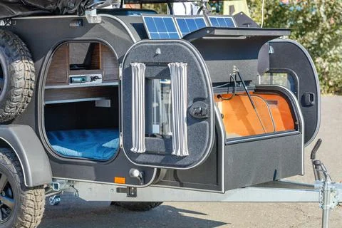 Compact road trailer mini-house for travel illuminated by summer sunbeams. Stock Photos