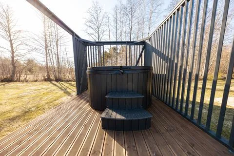Compact round hot tub on deck with matte black slatted railings Stock Photos