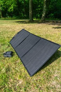 Compact solar panel recharging portable power station in nature. Sustainabl.. Stock Photos