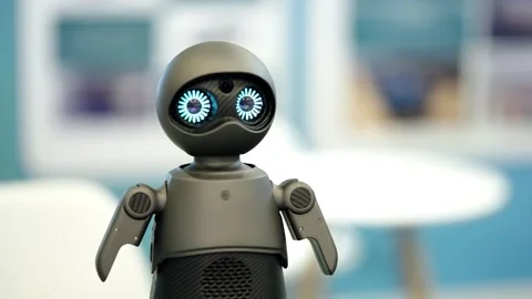 Compact tabletop companion robot with glowing blue eyes and articulated arms Video stock 325671378
