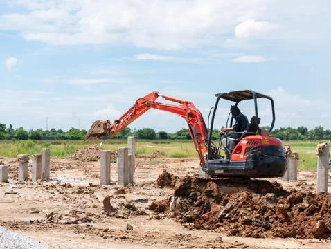 Compact track backhoe machine digging soil and clearing land for building f.. Fotos Stock