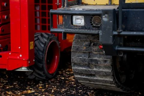 Compact track loader next to red mobile lift platform Stock Photos