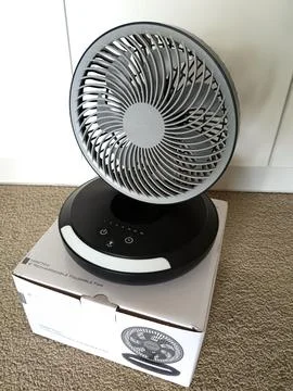 A compact white and black electric fan with spiral grille Stock Photos