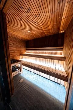 Compact wood lined sauna interior with three tier benches and warm lights Stock Photos