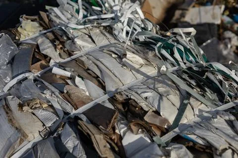 Compacted waste materials are securely bound with straps at a landfill site.. Stock Photos