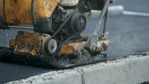 Compaction of asphalt with a road vibroplate. Ramming with your own hands Stock Footage 136276053