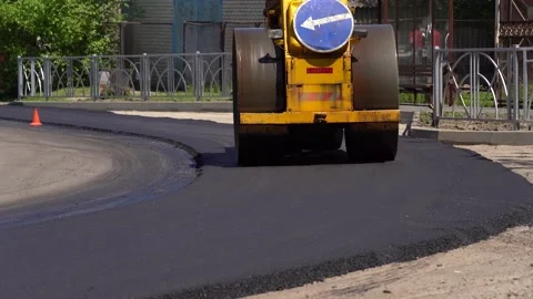 Compactor is driving over freshly poured asphalt and compresses it on the road Video stock 154411548