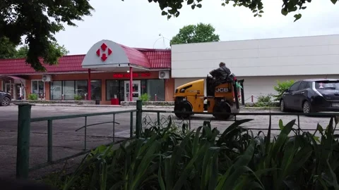 Compactor is driving over freshly poured asphalt on the road to fix a hole Stock Footage 156855922