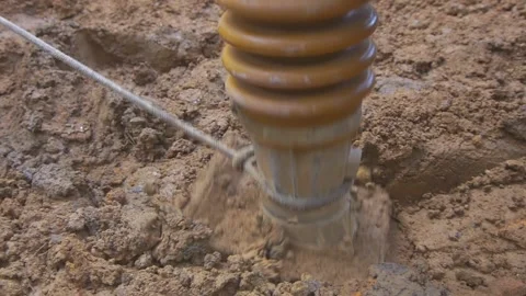 Compactor hammering on dry mud at a construction site Stock Footage 255684384