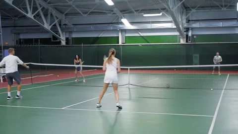 A company of friends play tennis on the sports ground, adult men and women throw Stock Footage