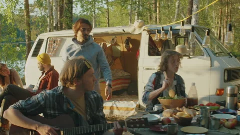 Company of Friends Preparing Food and Playing Guitar at Campsite Stock Footage