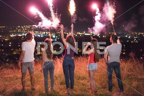 The company of people hold firework sticks. evening night time Stock Photos