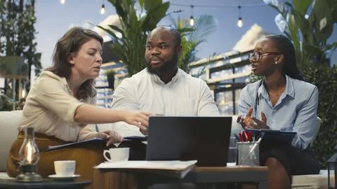 Company team laughs while looking at laptop on cozy rooftop lounge during break Stock Photos