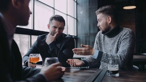 Company of three friends having an active discussion while sitting in the bar Stock Footage 74802418