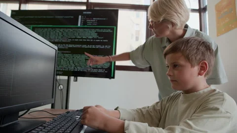 Comparing Data on Interactive Screen and That on Schoolboy Computer Stock Footage 316480663